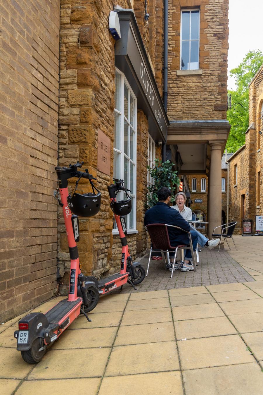 e-scooter outside of a building with people sat outside 