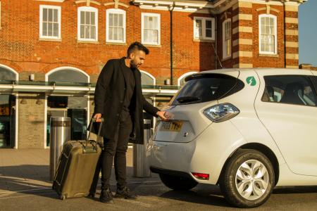 man getting into e-car with suitcase 