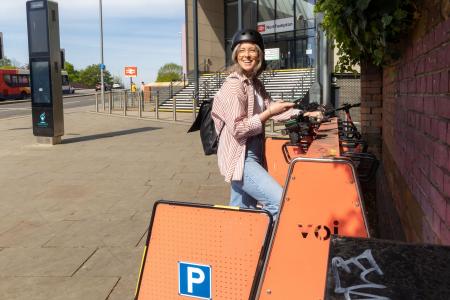 person standing outside of Northampton train station next to the e-scooter stand 
